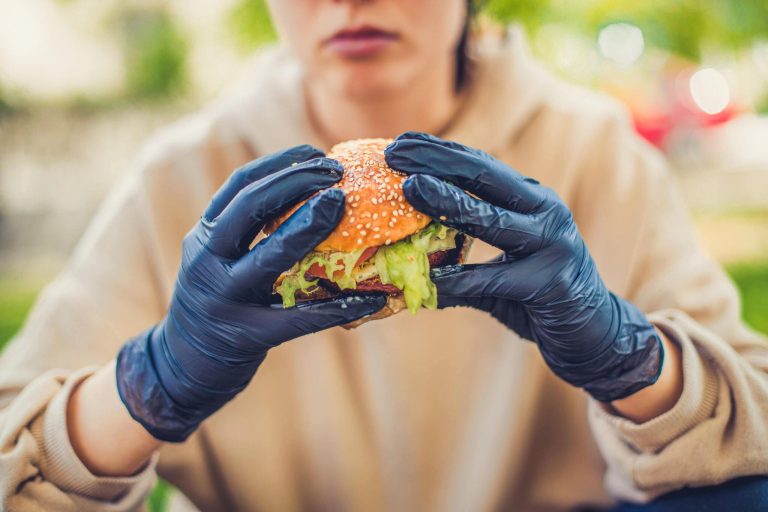 Girl wearing nitrile gloves and eating burger